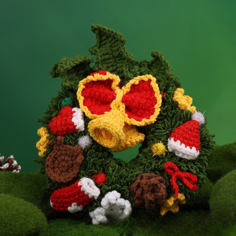 Crocheted Christmas wreath with colorful decorations on a green background